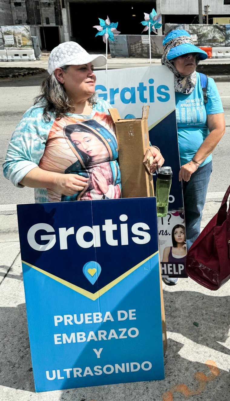 Pro-life demonstrators stand outside of a clinic with signs in Spanish
