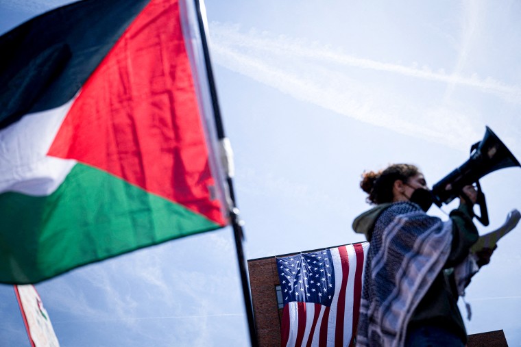 A demonstrator with a U.S. flag and Palestinian flag.