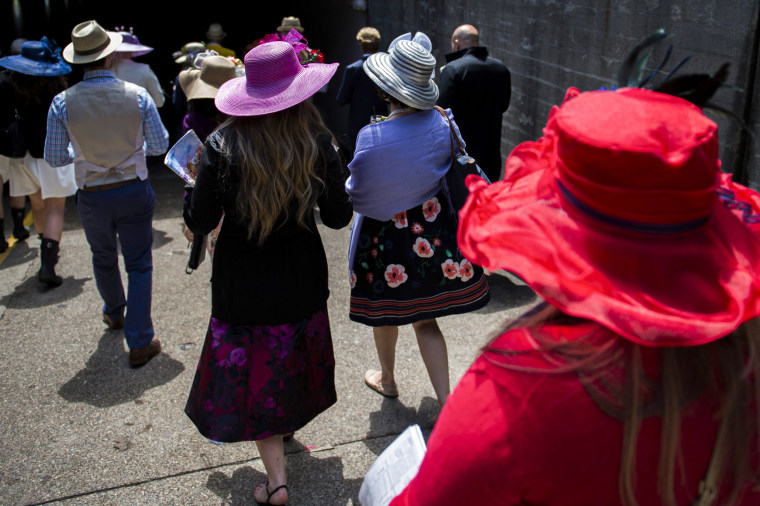 Derby goers leave the grandstand area wearing hats.