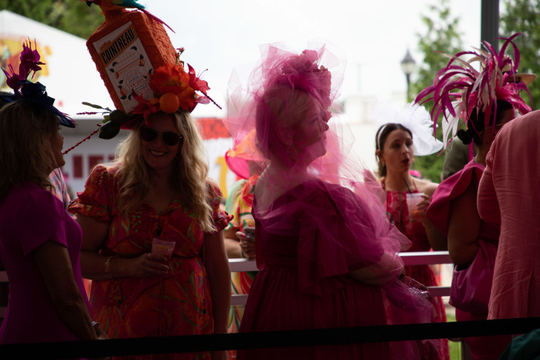 Women in large hats line up at Churchill Downs.