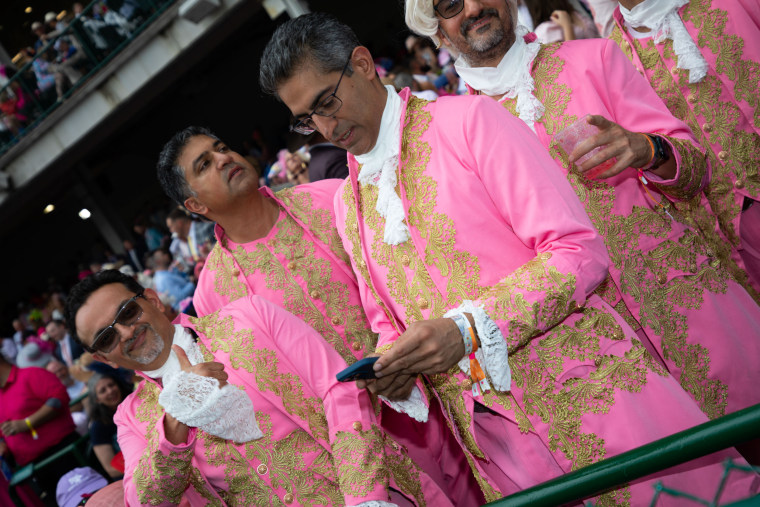 Men in colorful and embellished suits at Churchill Downs.
