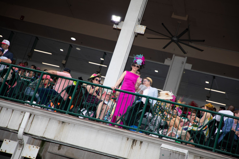 A woman in a flower hat poses in the grandstand.