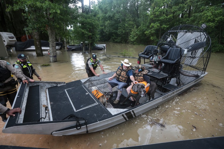 Game wardens use a boat to rescue residents from floodwaters