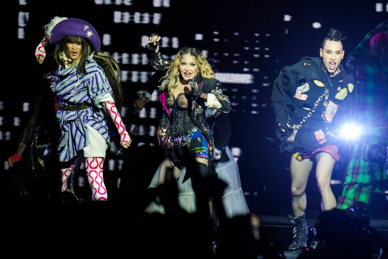 Madonna performs on stage with backup dancers beside her