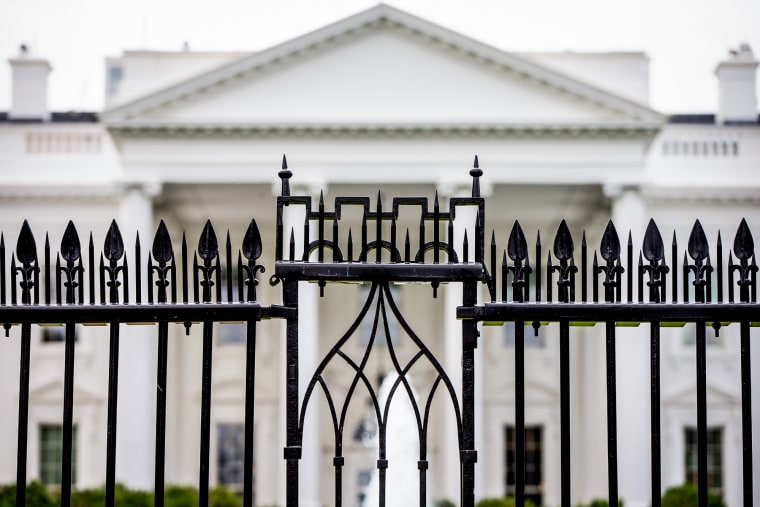 The White House is visible through the fence at the North Lawn