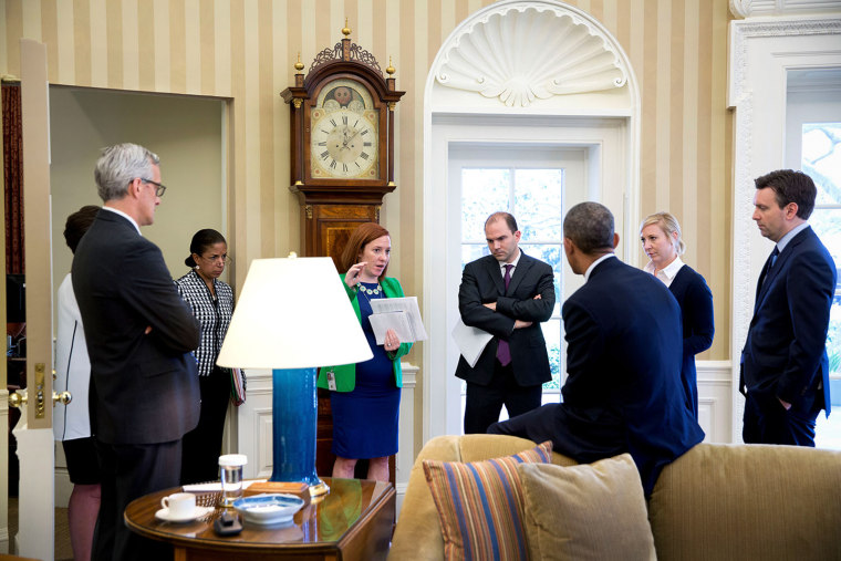 Barack Obama is surrounded by senior advisors in the Oval Office