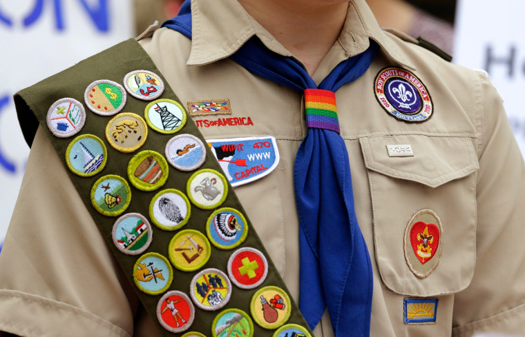 Merit badges and a rainbow-colored neckerchief slider on a Boy Scout uniform