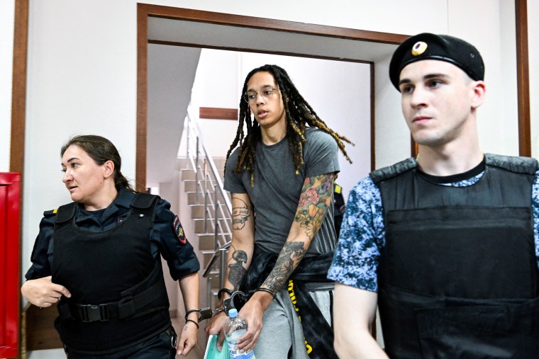 Brittney Griner is escorted by police officers in Russia while in handcuffs