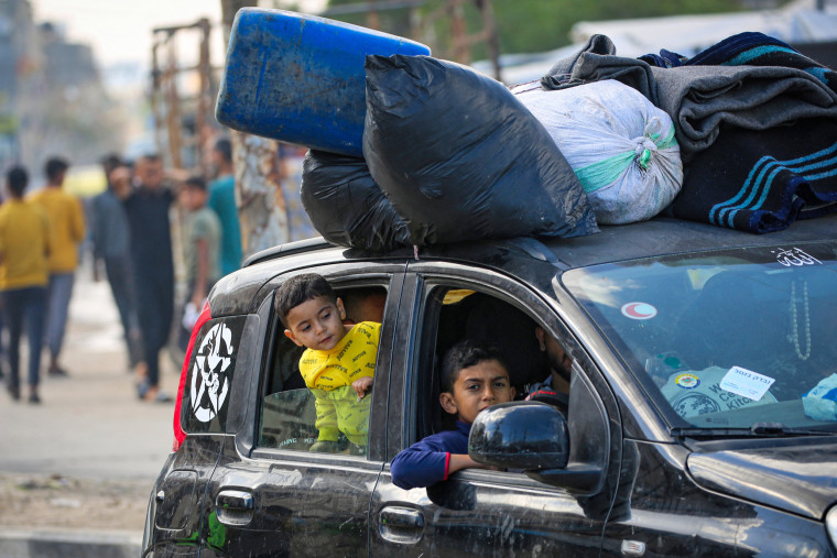 Displaced children look out of car windows as their family flees Rafah
