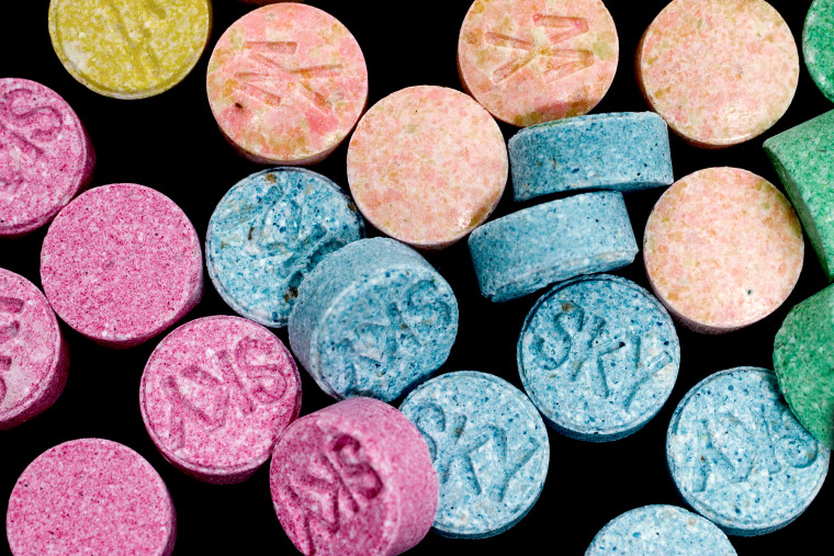 Colorful MDMA pills scattered around a black background