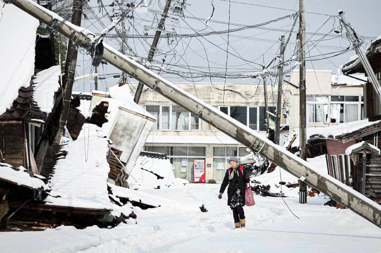 A woman walking under a downed utility pole after snow blanketed the disaster-hit area.