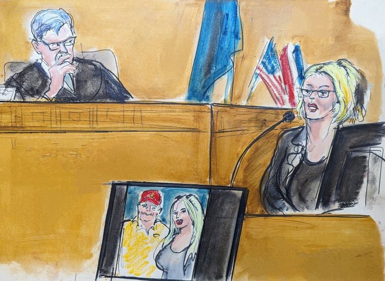 Courtroom sketch of Stormy Daniels testifies on the witness stand as Judge Juan Merchan looks on with a photo of Donald Trump and Daniels from their first meeting is displayed on a monitor