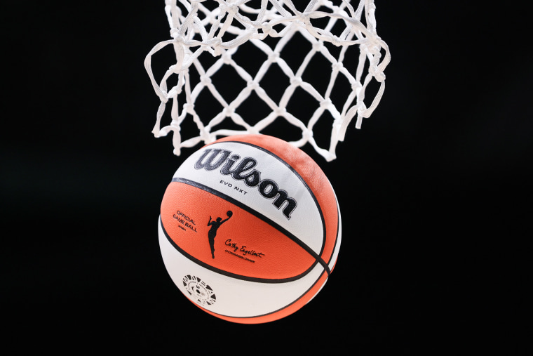 A detail of the WNBA logo is seen on a basketball falling through a hoop