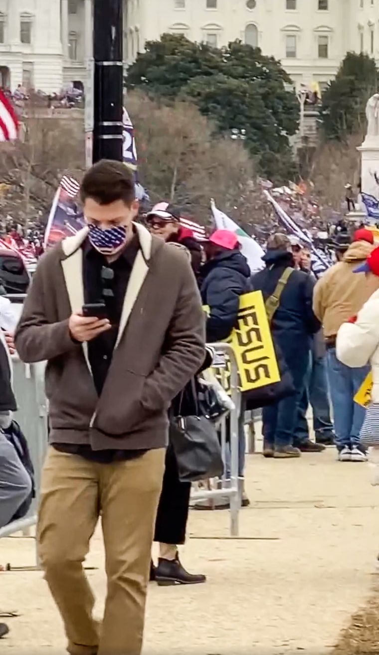 Zach Henry looks at his phone while walking through a crowd at the Capitol on January 6, 2021