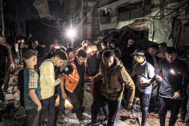 People and first responders carry away a rescued victim from the site of a building that was hit by Israeli bombardment in Rafah in the southern Gaza Strip