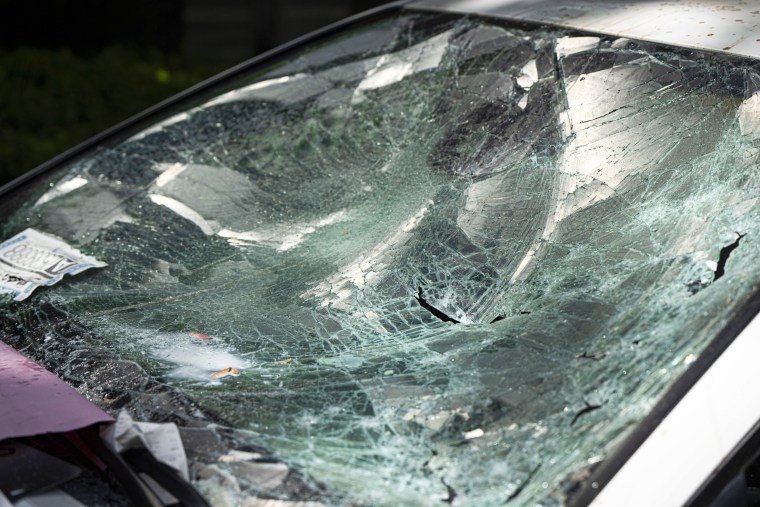 A car is seen parked and damaged on a campus walkway.