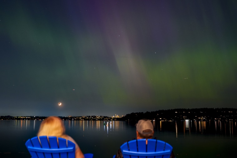 People view the northern lights, or aurora borealis over a lake in Washington