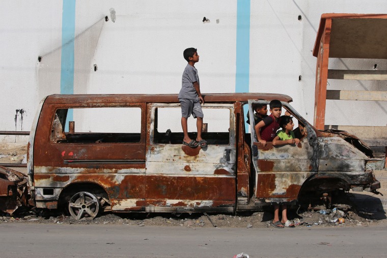 Palestinian children play in the remains of a charred vehicle in Rafah