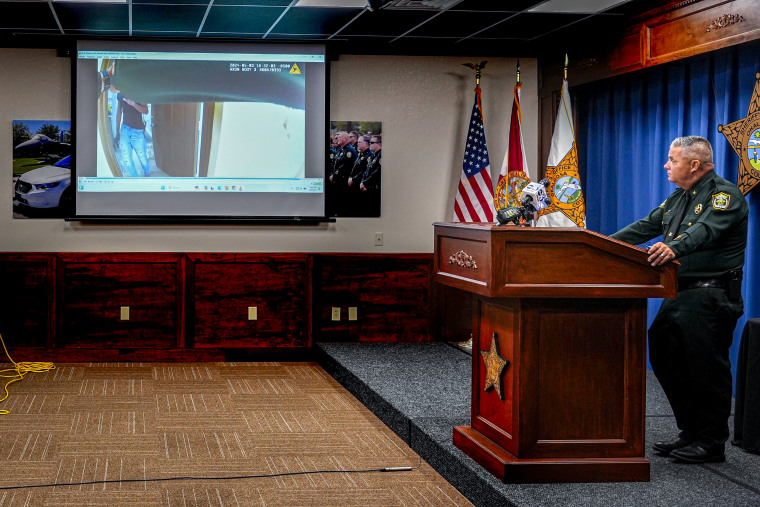 Footage of the shooting of Roger Fortson, displayed on screen at center.