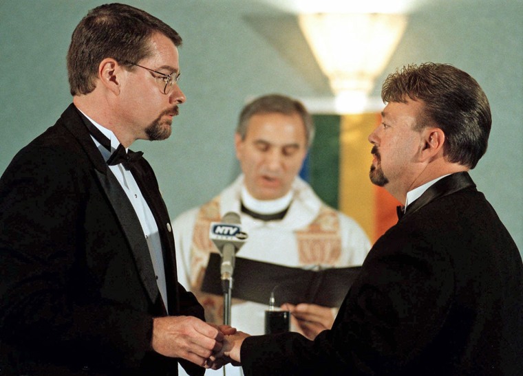 James Raymer, left, puts a ring on his partner Larry Ellis' finger during a recommitment ceremony on Nov. 16, 1999, in Grand Island, Neb., as Rev. Jimmy Creech officiates. The couple was married in April 1999 by Creech in North Carolina.  
