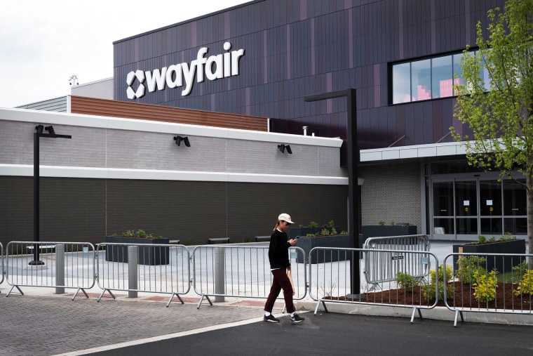 A person looks at their phone while walking in front of the new Wayfair store