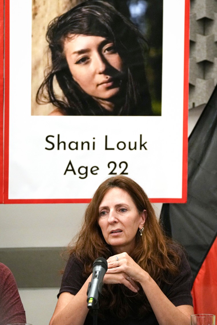Ricarda Louk sits in front of a placard of her missing daughter Shani Louk.