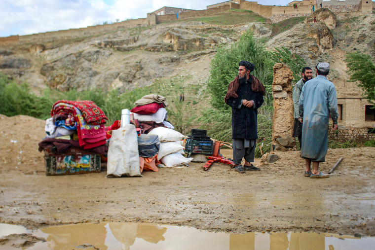 Afghan men stand beside their belongings.