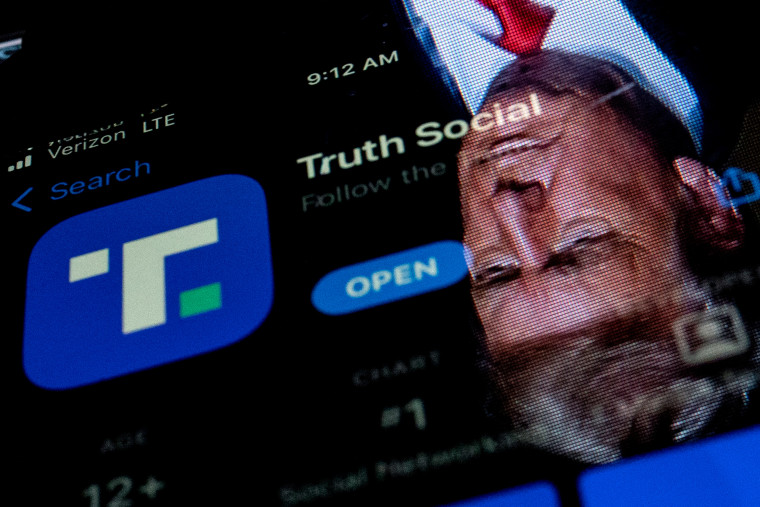 An image of former President Donald Trump reflected in a phone screen that is displaying the Truth Social app