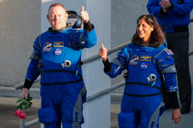 Butch Wilmore, left, and Suni Williams in their spacesuits give a thumbs up