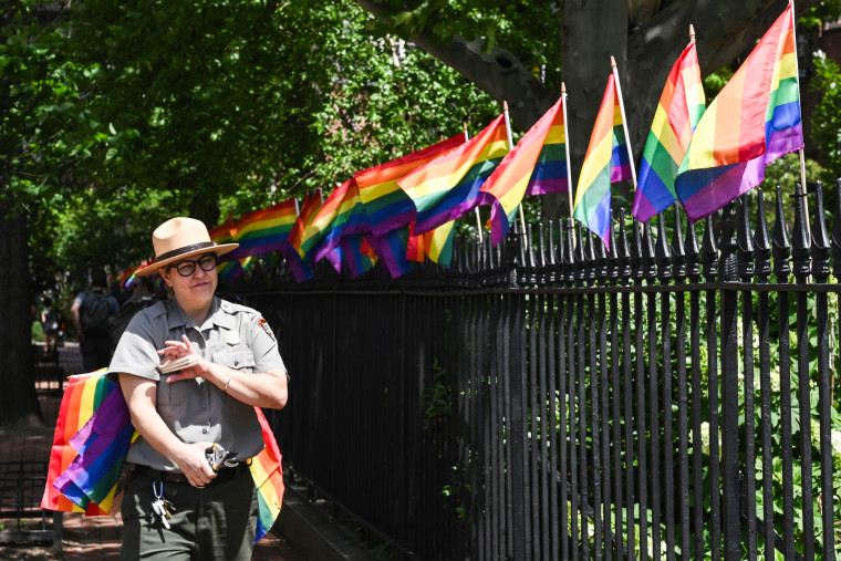 A park ranger places rainbow flags at the Stonewall National Monument