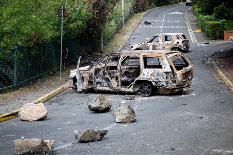 Burnt vehicles in an empty street.