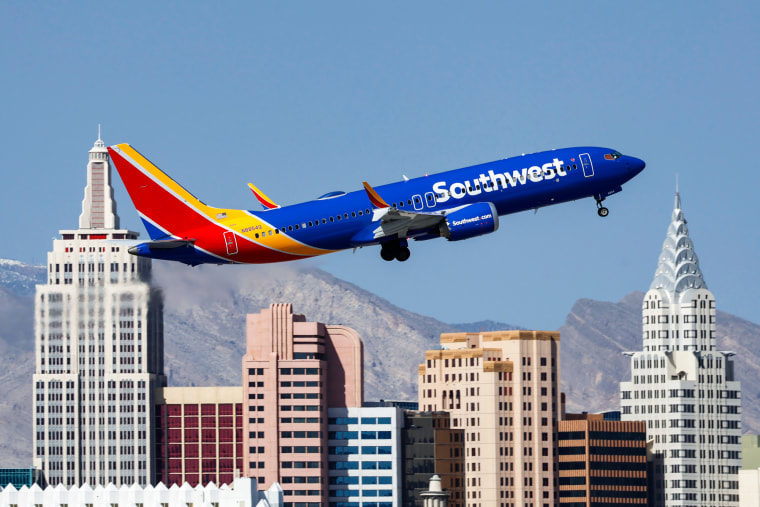 A Boeing 737 MAX 8 Southwest airplane flies above buildings