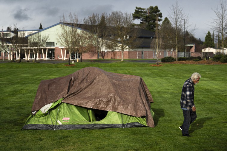 A homeless man walks by the tent