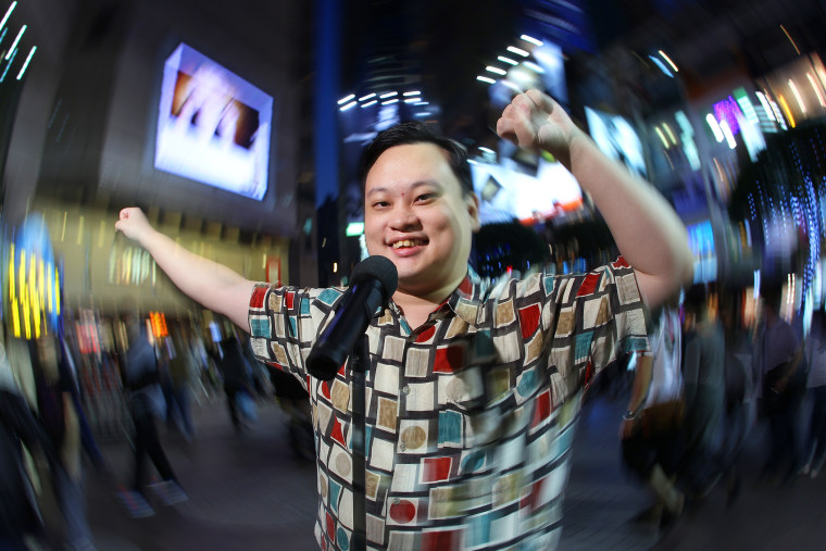 William Hung swings his arms in the air while performing outdoors