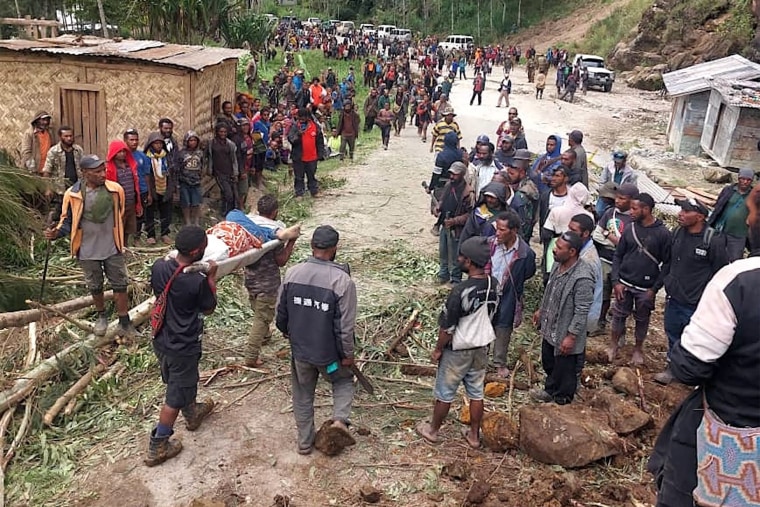 Men carry a person on a stretcher from the site of a landslide at Yambali Village in Papua New Guinea.