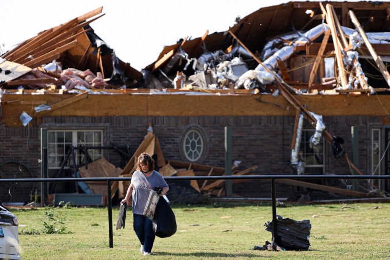 A women removes items from a home with storm damage.