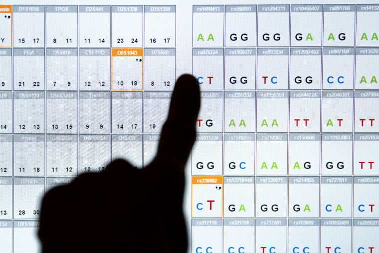 Close up of a finger silhouette pointing at the results of a DNA sequence analysis on a computer screen
