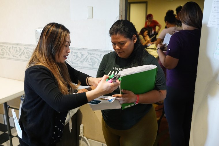 Image: A volunteer checks in an attendee during an orientation session for recent immigrants