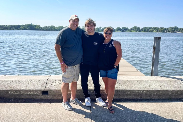 Three family members stand by a dock near the water