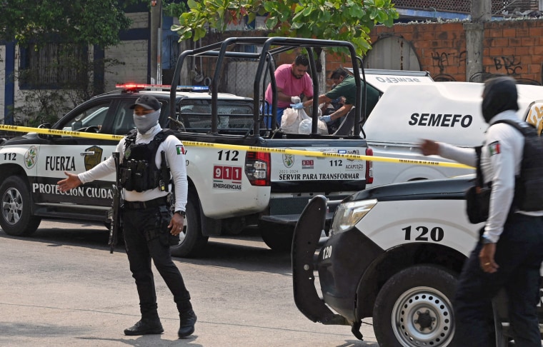 Police stand guard as forensic personnel remove the bodies of the PRI candidate for mayor of Coyuca de Benitez, Anibal Zuniga Cortes, and his wife, Ruby Bravo, killed in Acapulco, Guerrero state, Mexico, on May 16, 2024.