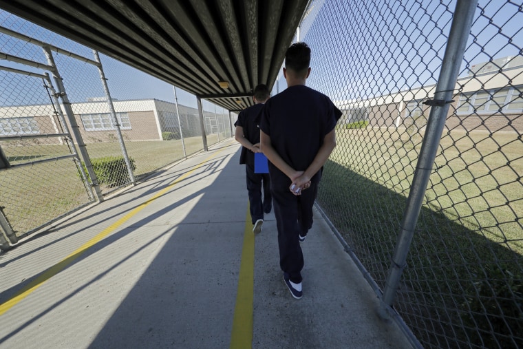 Detainees walk with their hands clasped behind their backs along a line painted on a walkway inside the Winn Correctional Center in Winnfield, La.