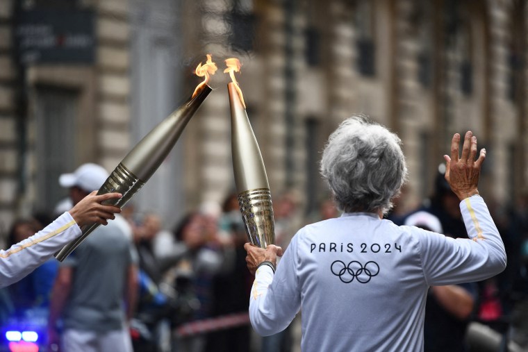 Two torch bearers carry the Olympic flame in Bordeaux, France on May 23, 2024.