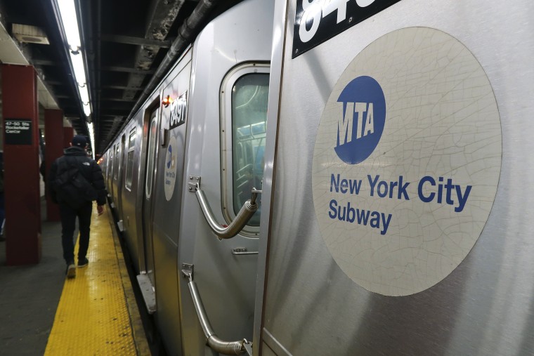 A commuter walks alongside a New York City subway train in 2018.