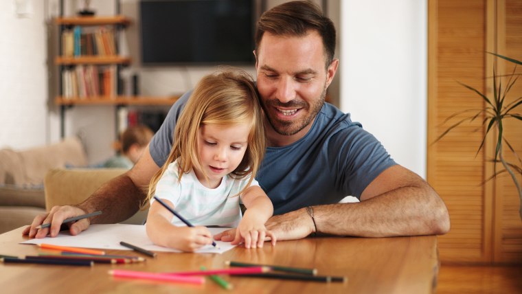 Father and daughter drawing/writing at home together.