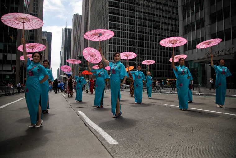 Woman dancing with pink umbrellas in the AAPI Parade.