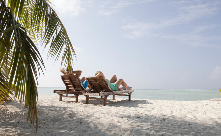 Couple relax on white sand beach, palm tree