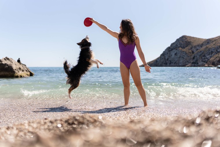 woman playing with her dog on the beach