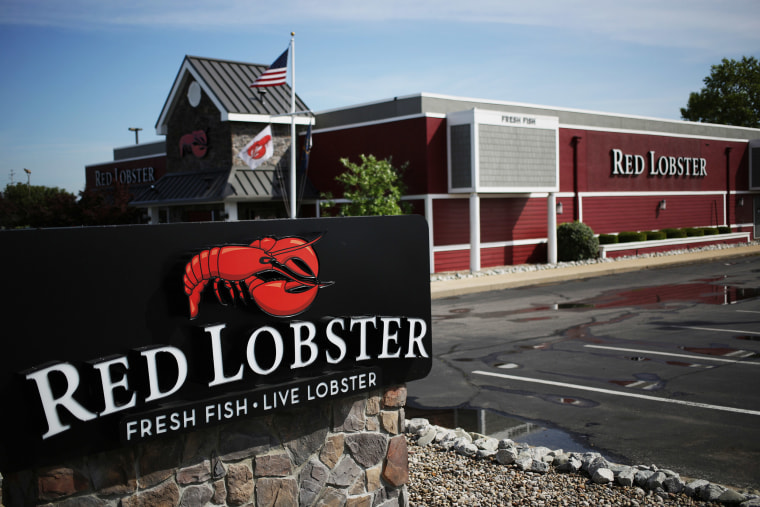An American flag flies past Red Lobster signage displayed outside of a restaurant