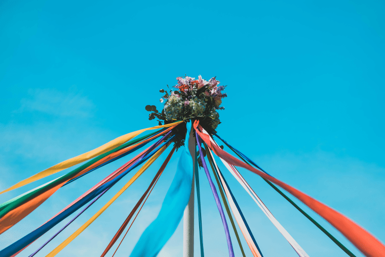 Maypole with flowers on top against a blue sky.