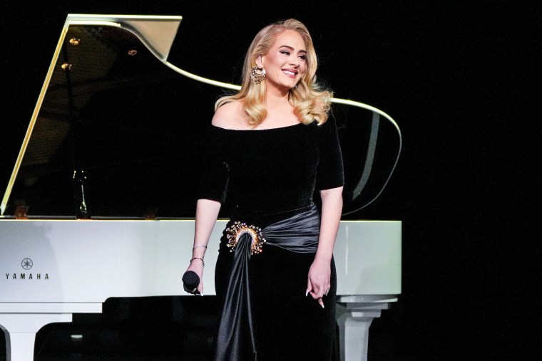Adele stands on stage in front of a piano